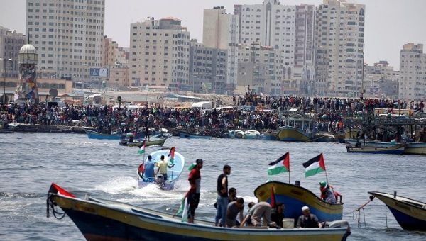 People watch as Palestinians prepare to sail a boat towards Europe aiming to break Israel's blockade on Gaza, at the sea in Gaza May 29, 2018.