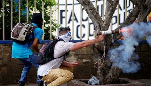 Nicaraguan protester fires homemade mortar at riot police.