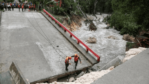 Members of Guatemalan emergency commission (CONRED) stand at a bridge that collapsed after heavy rains brought by Hurricane Earl at Menchor de Mencos, Guatemala, August 4, 2016. 