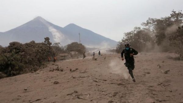 A police officer runs away after the Fuego volcano spew new pyroclastic flow in Guatemala.