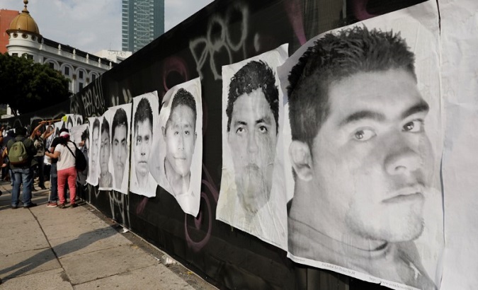 People paste posters on a wall with images of some of the 43 missing Ayotzinapa students during a march to mark the 43rd month since their disappearance.
