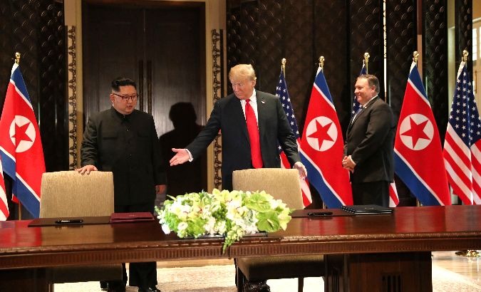 Donald Trump (R) and Kim Jong-un enter conference room to sign unspecified document.