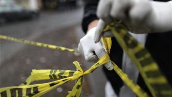 A forensic technician ties a used police line together to seal off a crime scene in Monterrey February 8, 2012. 