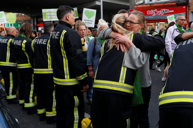 A participant hugs a firefighter as they walk near the tower in London.