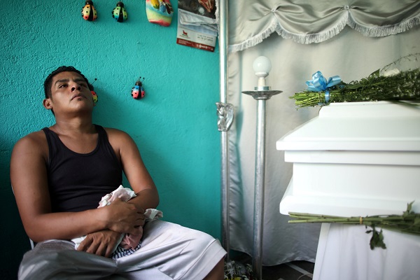 Nelson Gabriel Lorio Sandoval sits next to the coffin of his one-year-old son, Teyler, killed by a stray bullet in Managua.