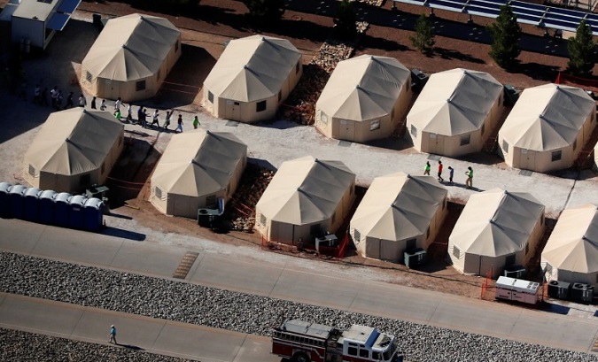 Children walk in single file between tents in a detention center next to the Mexican border in Tornillo, Texas, June 18, 2018.