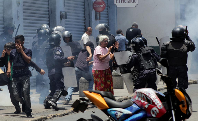 People react as riot policemen try to detain a demonstrator during a protest against Honduran President Juan Orlando Hernandez on May Day in Tegucigalpa, Honduras May 1, 2018