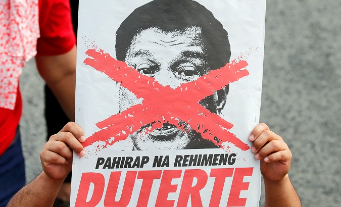 An activist displays an image of President Duterte with an 