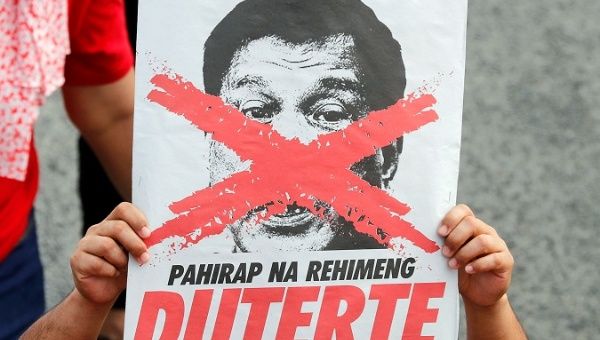 An activist displays an image of President Duterte with an 