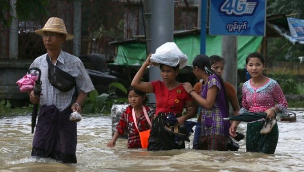 People wade through a flooded street in Bago, Myanmar, July 27, 2018. Picture taken July 27, 2018.
