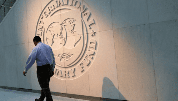 A person walks past the International Monetary Fund (IMF) logo at its headquarters in Washington, U.S., May 10, 2018.