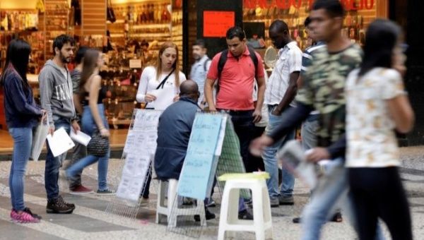 People look at lists of job openings posted on a street in downtown Sao Paulo, Brazil.