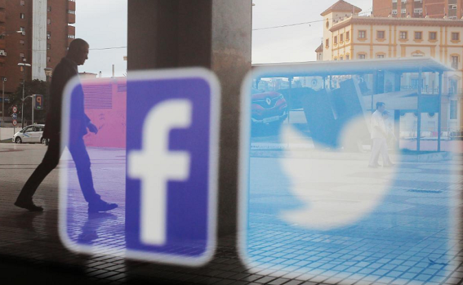 Facebook and Twitter logos are seen on a shop window in Malaga, Spain, June 4, 2018.