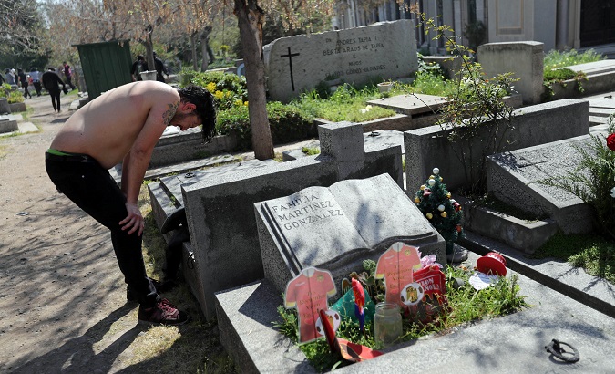 A demonstrator takes refuge in the cemetery after Chilean police attacked them with tear gas Sunday.