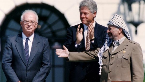 PLO Chairman Yasser Arafat (R) gestures to Israeli Prime Minister Yitzhak Rabin (L), following their handshake after the signing of the peace accord.