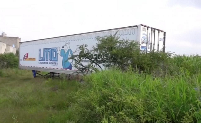 An officer walks past an abandoned trailer full of bodies in Tlajomulco, Jalisco, Mexico Sept. 15, 2018 in this still image taken from a video obtained September 17, 2018