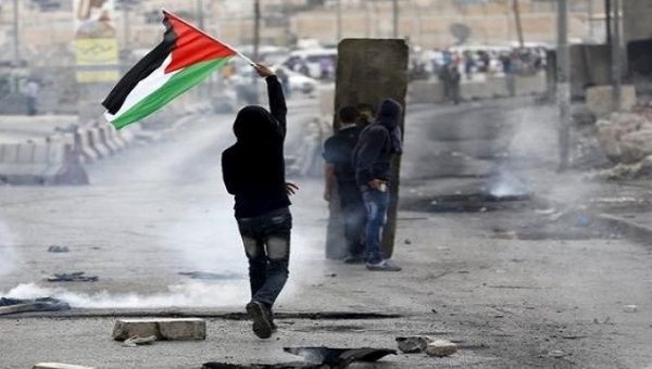 Protester with Palestinian flag during clashes with Israeli army at Qalandia checkpoint near occupied West Bank city of Ramallah, Oct. 6, 2015.