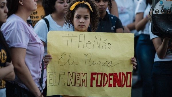 Brazilian girl holds a sign with the anti-Bolsonaro hashtag #EleÑao.