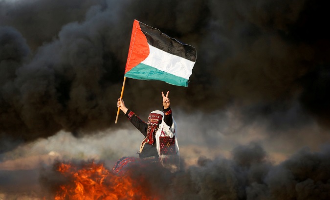 A woman waves a Palestinian flag during a protest at the Israel-Gaza border fence.