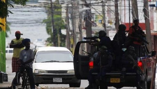 Armed police question men on the street in the Tivoli Gardens neighborhood of Kingston, Jamaica.