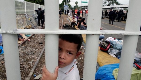 A Honduran migrant child, part of a caravan trying to reach the US, looks though the gate on the bridge that connects Mexico and Guatemala in Tecun Uman, Guatemala, October 20, 2018. 
