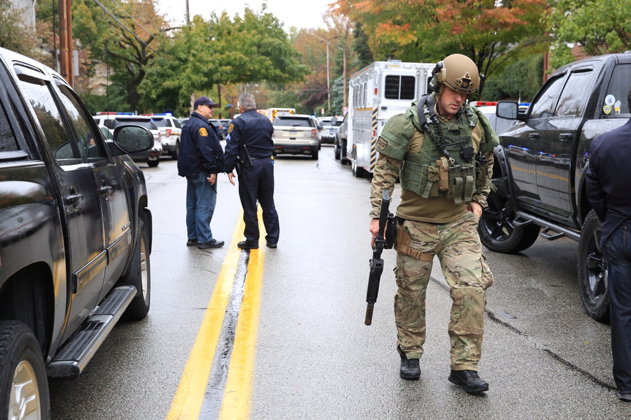 A SWAT police officer and other first responders arrive at the synagogue after a gunman opened fire.