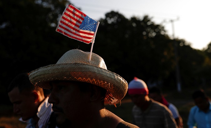 A migrant from Honduras, part of a caravan traveling to the US, wears a hat with the US flag while he walks along the road to Huixtla, near Tapachula, Mexico, October 31, 2018.