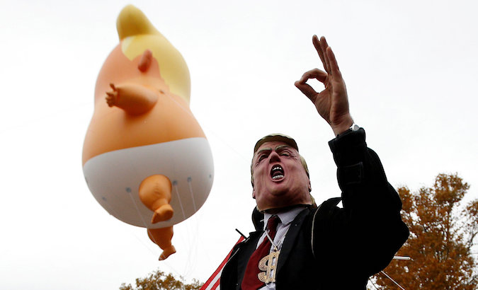 People take part in a protest against US President Donald Trump, as part of the commemoration ceremony for Armistice Day.