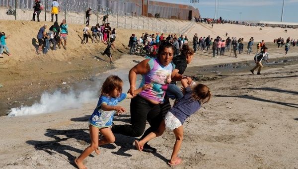 A migrant family, part of a caravan of thousands traveling from Central America en route to the United States, run away from tear gas in front of the border wall between the U.S and Mexico in Tijuana, Mexico November 25, 2018.