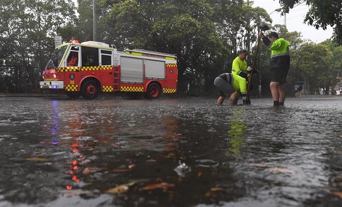 Workers try to unclog a drain after rains that lasted hours in Sydney, Australia, Nov. 28.