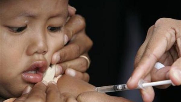 A child looks on as a paramedic injects the measles vaccine into her arm in Yogyakarta, Indonesia.