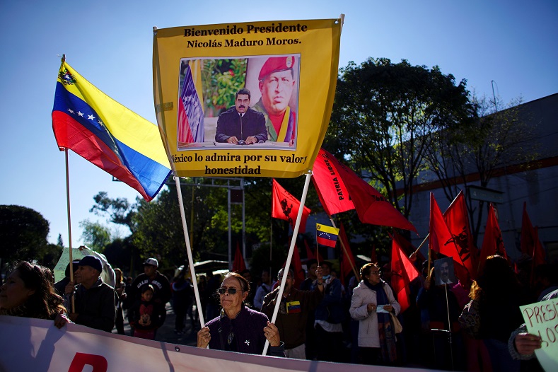 A supporter of Venezuelan President Nicolas Maduro, whose invitation to the ceremony by AMLO has been seen as controversial, holds up a banner. 