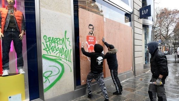 Workmen place a wood panel to protect a broken window on a GAP clothing store the day after clashes during a national day of protest by the 