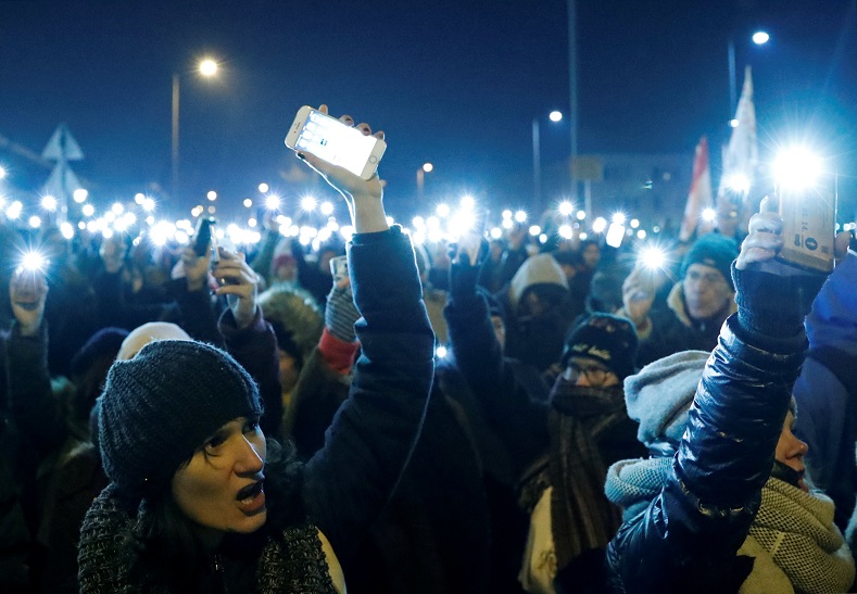 People hold up their mobile phones attend a protest against a proposed new labor law, billed as the 