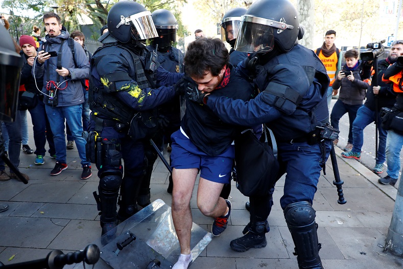 Police officers detain a demonstrator during a protest against Spain's cabinet meeting.
