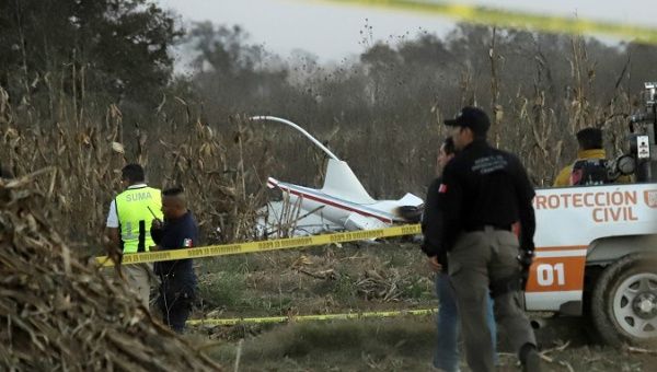 Police and rescue personnel stand at the scene where the helicopter crashed, in Coronango, Puebla Mexico, December 24, 2018.