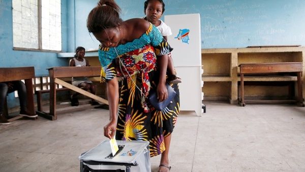 A woman carries her baby as she casts her vote at a polling station during the presidential election in Kinshasa, Democratic Republic of Congo, Dec. 30, 2018.