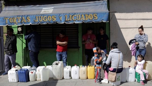 People stand next to empty containers near a gas station, in Morelia, Mexico January 9, 2019.