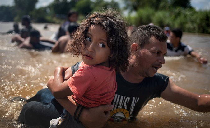 Luis Acosta holds 5-year-old Angel Jesus as migrants from Central America en route to the United States crossed a River into Mexico from Guatemala.