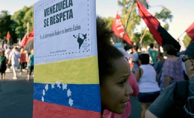 An Argentine protester holds a sign, decorated in the colors of the Bolivian flag with the words, 