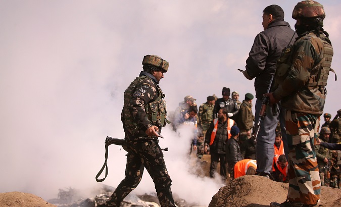 Indian soldiers stand as smoke billows from the wreckage of Indian Air Force's helicopter after it crashed in Budgam district in Kashmir Feb. 27, 2019.