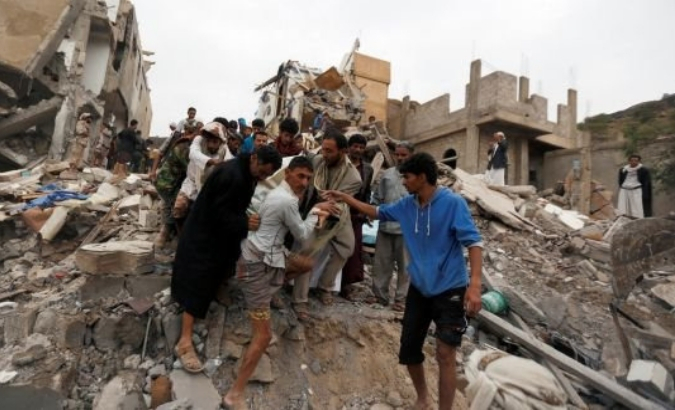 People carry the body of a woman they recovered from under the rubble of a house destroyed by a Saudi-led air strike in Sana’a, Yemen