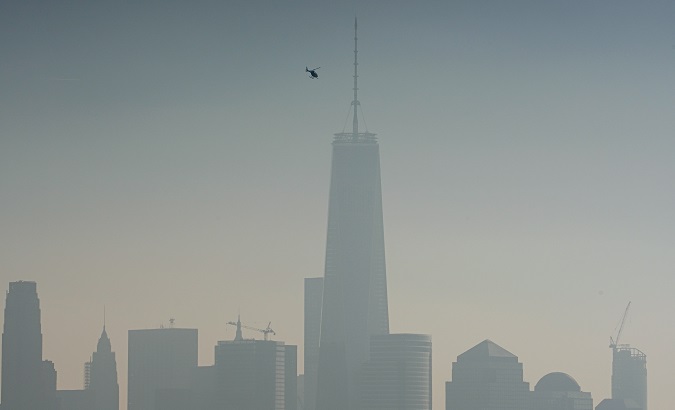 A helicopter flies over the Hudson River with One World Trade Center and Lower Manhattan in the background, on a hazy day in New York City, Dec. 6, 2015.