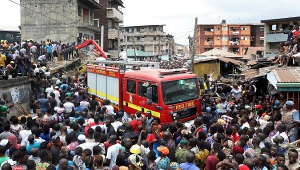 People gather as rescue workers search for survivors at the site of a collapsed building containing a school in Nigeria's commercial capital of Lagos, Nigeria March 13, 2019. 