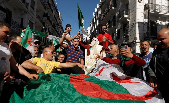 People carry their national flags as they protest against President Bouteflika in Algiers, Algeria, March 15, 2019.