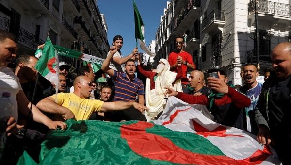 People carry their national flags as they protest against President Bouteflika in Algiers, Algeria, March 15, 2019. 
