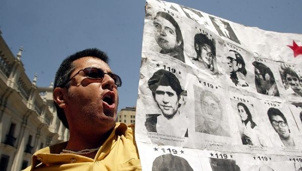 Opositores al ex dictador chileno Augusto Pinochet Ugarte portan fotografias de victimas de la dictatura frente al Palacio de La Moneda.