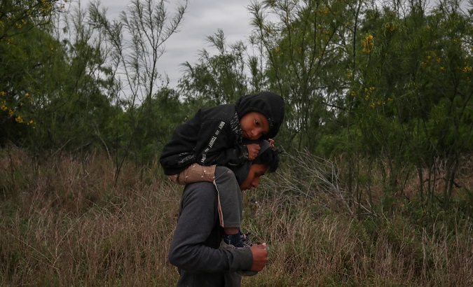Ostavio, 5, from Guatemala, rests on the shoulders of his brother Eduardo as they walk through a field in hopes of finding refuge in the United States.