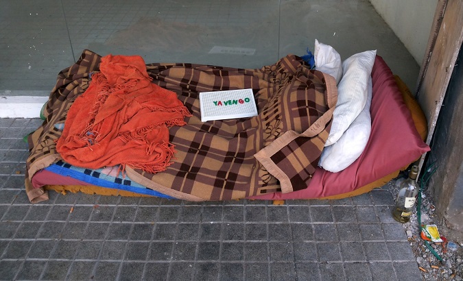 A make-shift bed of a homeless person, with a sign on top that reads 