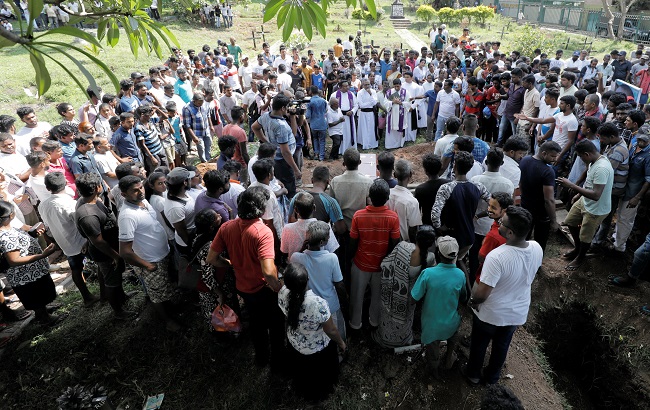 People attend a mass burial of victims, two days after a string of suicide bomb attacks on churches and luxury hotels across the island on Easter Sunday, in Colombo